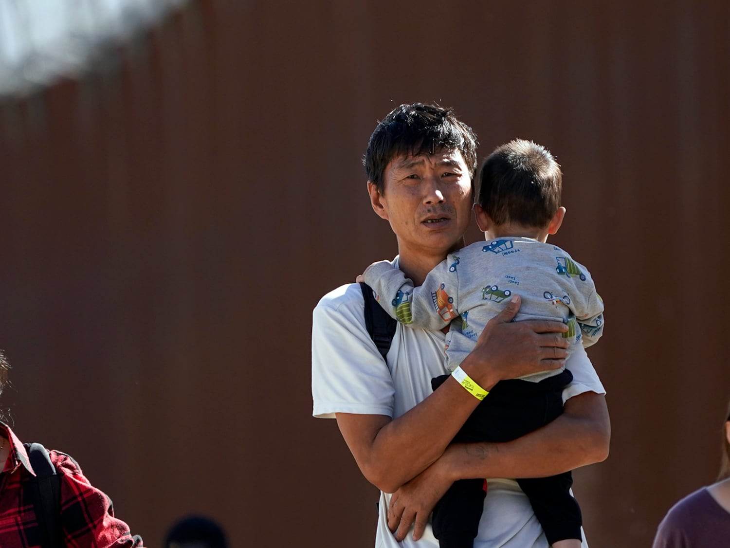 A group of people,  many from China, walk along the USA - Mexico border wall after crossing into the USA to seek asylum, Tuesday, Oct. 24, 2023, near Jacumba, Calif..