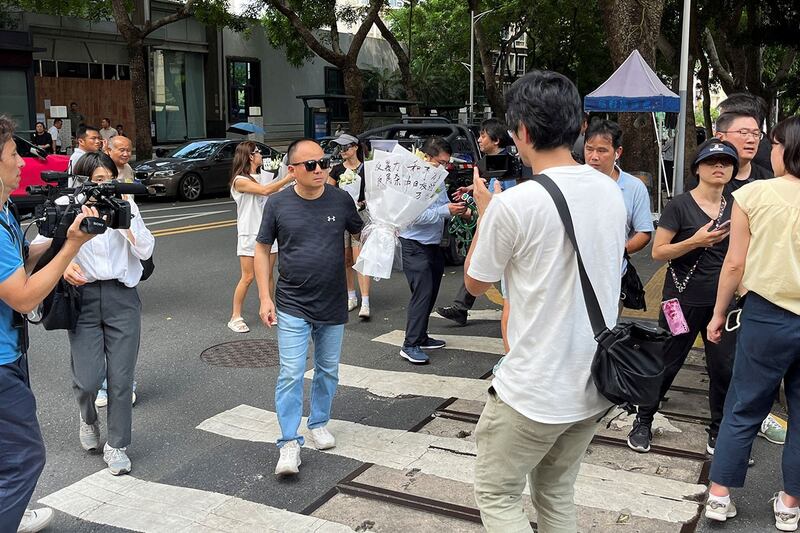 一名日本男孩在前往深圳日本人学校上学途中遇刺后于2024年9月19日去世。图为手持花束站在该校校外的一名男子。（路透社）