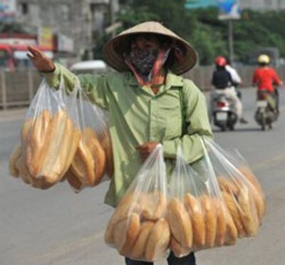 Một người bán bánh mì mời người đi xe mua dọc theo một đường cao tốc ở ngoại ô Hà Nội ngày 19 tháng 4 năm 2010. AFP PHOTO / HOANG DINH Nam.