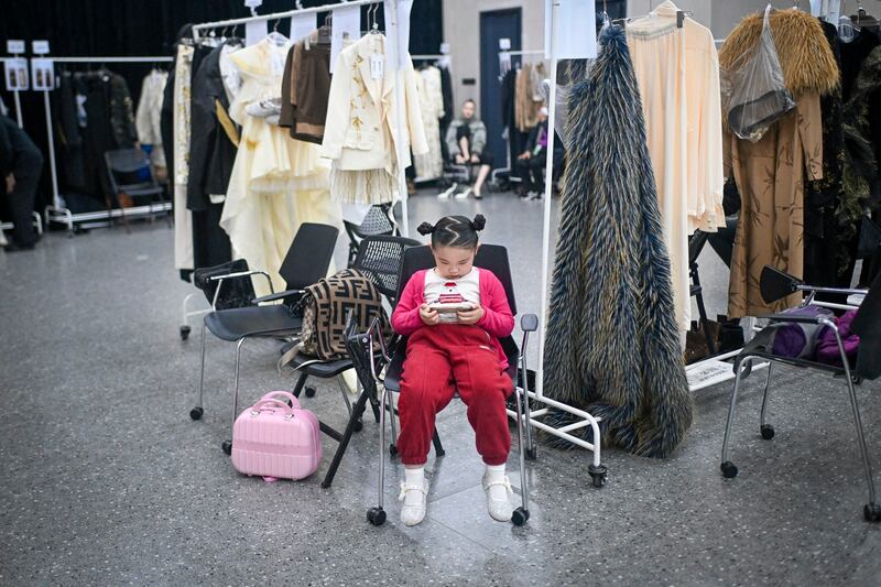 A young model uses her mobile phone as she waits backstage during the China Fashion week in Beijing on March 29, 2024. (Wang Zhao/AFP)