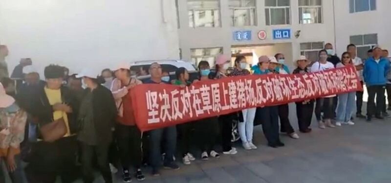 牧民打出的横幅写有“坚决反对草原上建猪场，反对破坏生态”。（视频截图/记者乔龙）