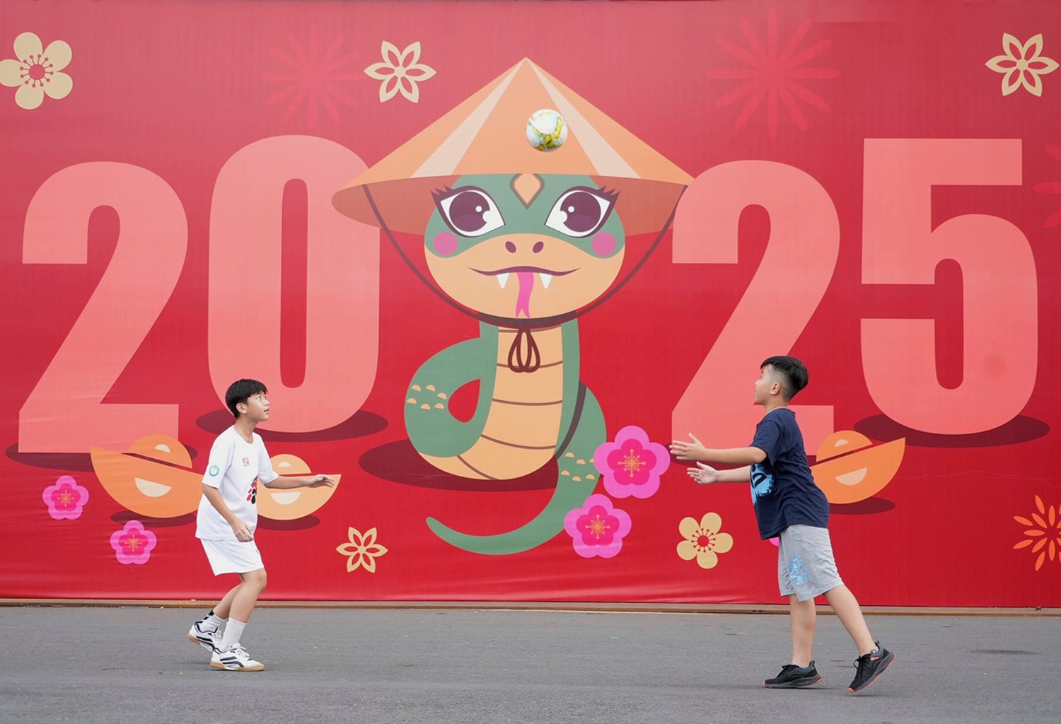 Two boys play in front of a billboard welcoming the New Year 2025 in Ho Chi Minh on Dec.31, 2024.