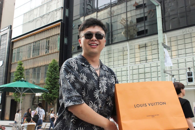 Chinese tourist Zhang Lei poses with a recent purchase in the Ginza shopping district of Tokyo, Japan, July 27, 2024. (David Dolan/Reuters)