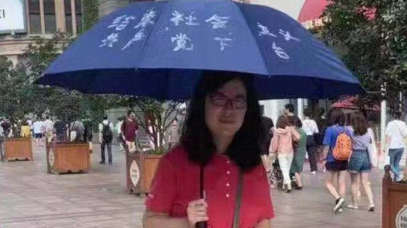 张展在上海南京东路步行街举伞，促结束“社会主义，共产党下台”。（志愿者提供/记者乔龙）