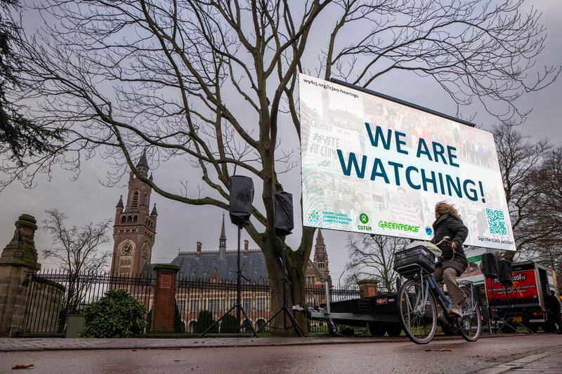 Activists protest outside the International Court of Justice, left, in The Hague, Netherlands, as it opens hearings into what countries worldwide are legally required to do to combat climate change and help vulnerable nations fight its devastating impact, Monday, Dec. 2, 2024.