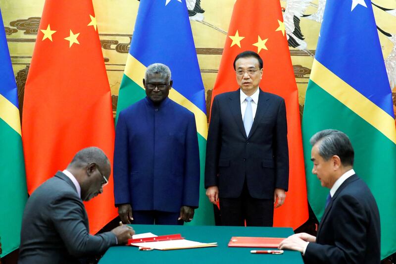 Solomon Islands Prime Minister Manasseh Sogavare (standing, left) and Chinese Premier Li Keqiang (standing, right) attend a signing ceremony at the Great Hall of the People in Beijing, Oct. 9, 2019. Credit: Reuters.