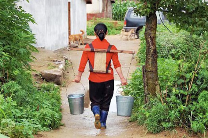 A woman carries water at farm in North Korea in undated photo.