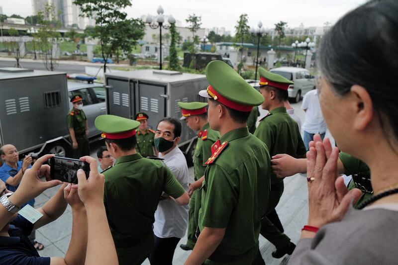 Police escort Vietnam's former Deputy Minister of Foreign Affairs To Anh Dung, center, after his trial related to fraud involving COVID-19 repatriation flights, in Hanoi on July 28, 2023. (Anh Tuc/AFP)