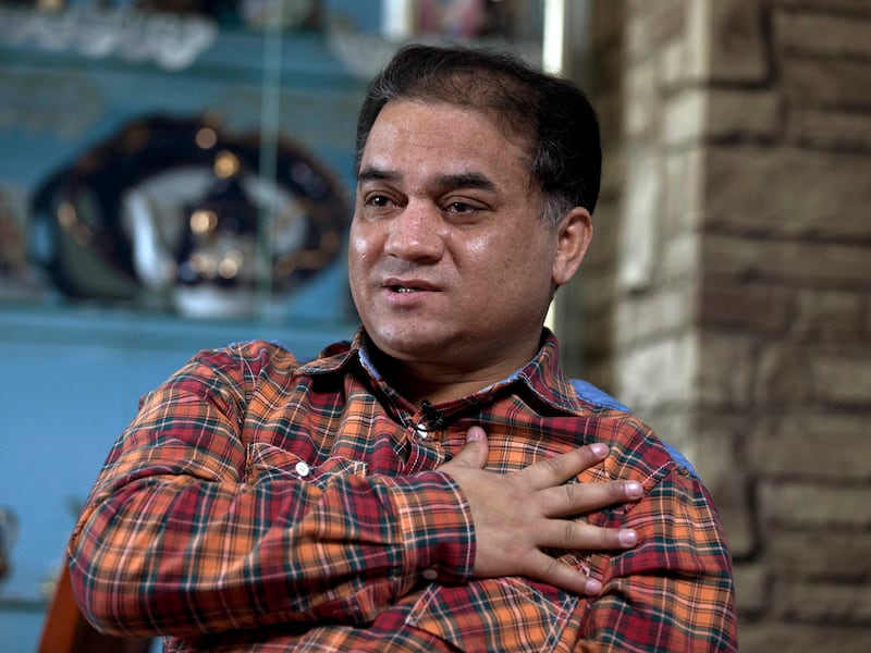 Ilham Tohti, a scholar from China's Turkic Uighur ethnic minority shows how the officers stopped him at the airport, during an interview at his home in Beijing Feb. 4, 2013.