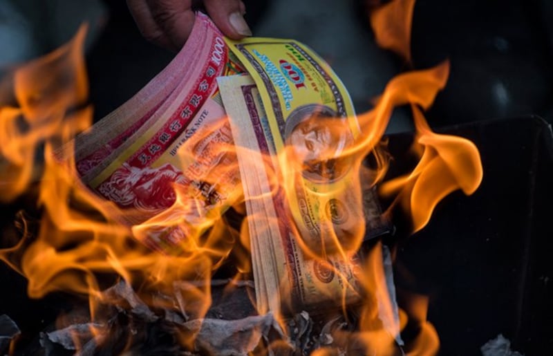 A man burns ghost money to pay his respects to his ancestors in front of a gravestone during the Qingming Festival in Shanghai, China, April 4, 2017. (Johannes Eisele/AFP)