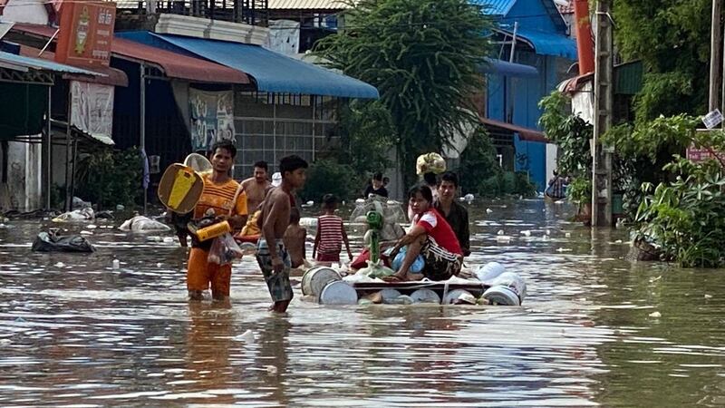 Residents carry belongings by hand and on makeshift rafts through flooded streets in Phnom Penh, Oct. 14, 2020.