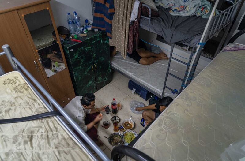 Myanmar migrant workers eat a meal in their 10.5-by-10.5 foot room, which typically accommodates six people. Photo by Gemunu Amarasinghe