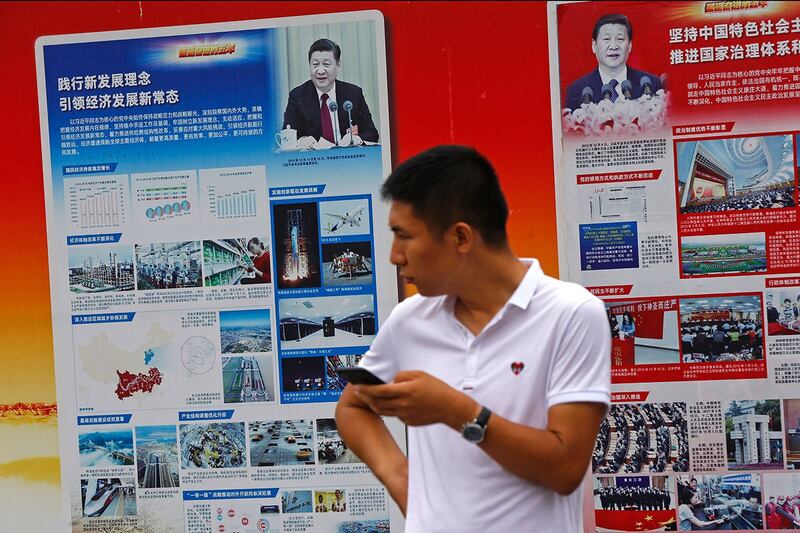 北京地铁站外，一名男子站在宣传习近平和中国经济成就的政府宣传广告牌附近。（美联社）