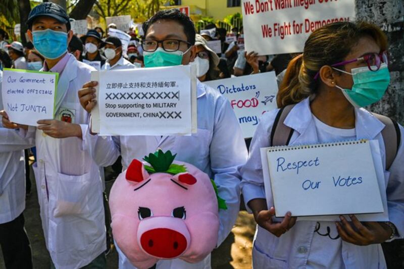 Doctors and healthcare workers hold signs as they take part in a demonstration against the military coup in front of the Chinese Embassy in Yangon, Myanmar, Feb. 11, 2021. Credit: AFP