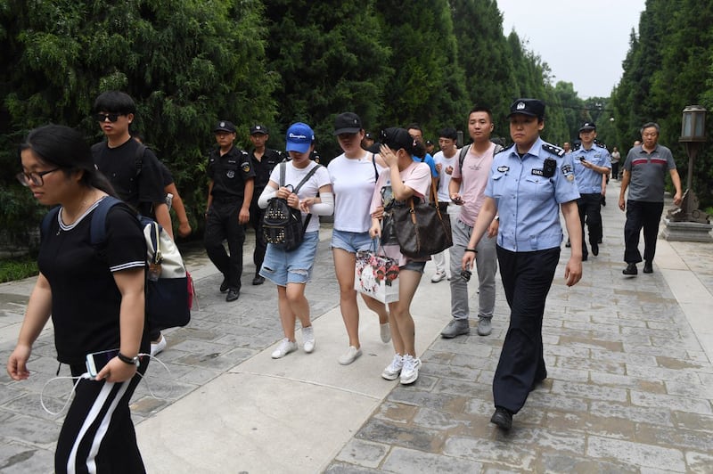 Petitioners are escorted out of a park by police and security personnel before being loaded on buses and driven away in Beijing as hundreds of police swarmed the streets of Beijing's financial district to quash a rally by angry peer-to-peer lenders, Aug. 6, 2018. Credit: AFP