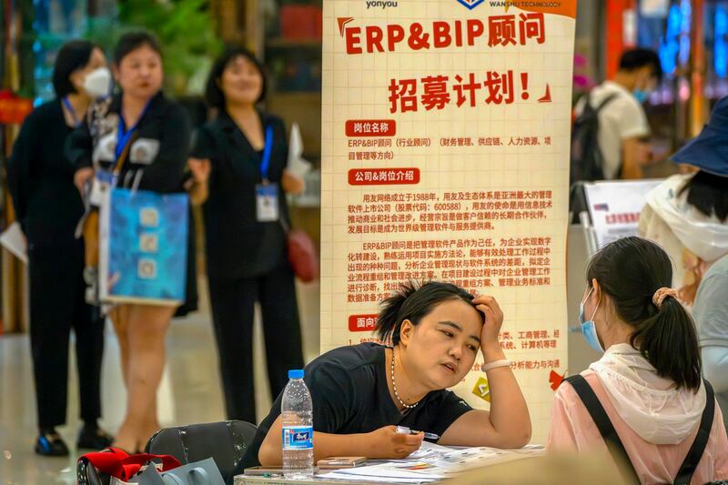 A recruiter talks with an applicant at a booth at a job fair at a shopping center, June 9, 2023 in Beijing. (Mark Schiefelbein/AP)