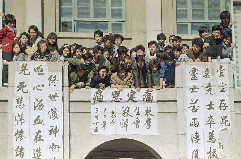 1989年4月26日，在北京政法学院，学生们在悬挂横幅的阳台上向下张望，参加学生记者会。（美联社）