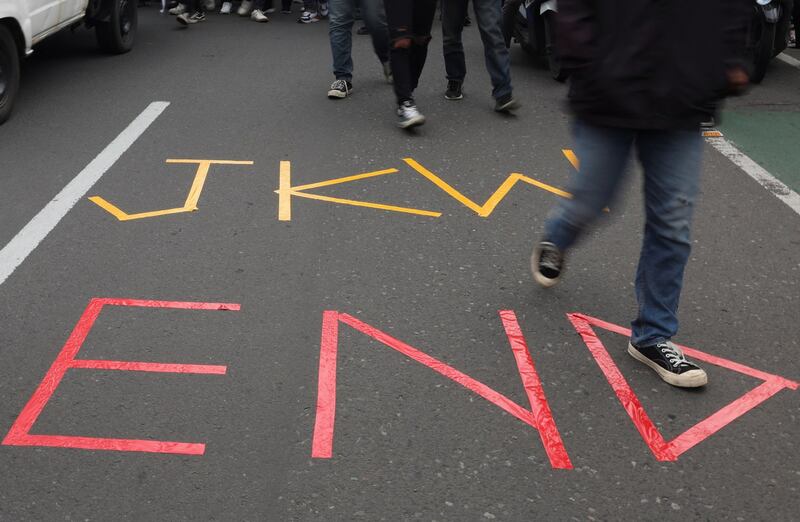 Indonesian university students walk past a sign painted on the road that says “JKW END” during a protest against outgoing President Joko “Jokowi” Widodo's perceived interference in the electoral process for next week's election, Jakarta, Feb. 7, 2024. (Ajeng Dinar Ulfiana/Reuters)