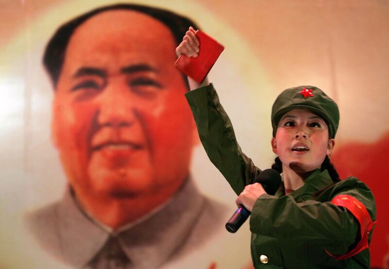 A woman dressed as a Red Guard, holding a "Little Red Book" performs in front of a portrait of the late Chairman Mao Zedong at a restaurant in Beijing in 2006. Credit:Jason Lee/Reuters