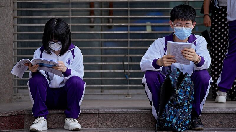 资料图片：2021 年 6 月 7 日，在北京举行的高考统考之前，学生们在校外复习课本。（美联社）