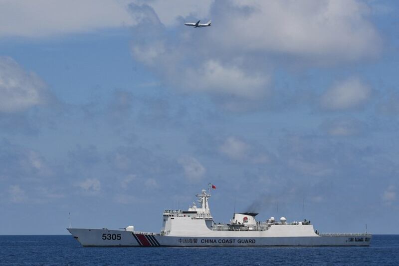 A U.S. Navy P-8 Poseidon patrol and reconnaissance plane circles past a Chinese coast guard ship during a resupply mission by a civilian boat chartered by the Philippine navy to deliver supplies to Manila's outpost on Second Thomas (Ayungin) Shoal in the disputed South China Sea, Aug. 22, 2023. (Ted Ajibe/AFP)