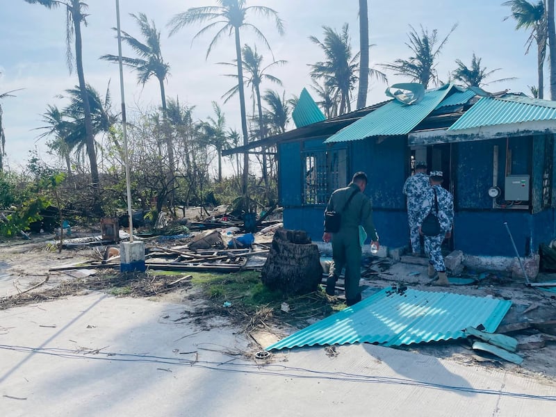 Philippine Coast Guard personnel walk towards a damaged structure due to typhoon Rai, on Philippine-claimed Thitu Island, South China Sea, December 21, 2021. Picture taken December 21, 2021. Credit: Philippine Coast Guard via Reuters