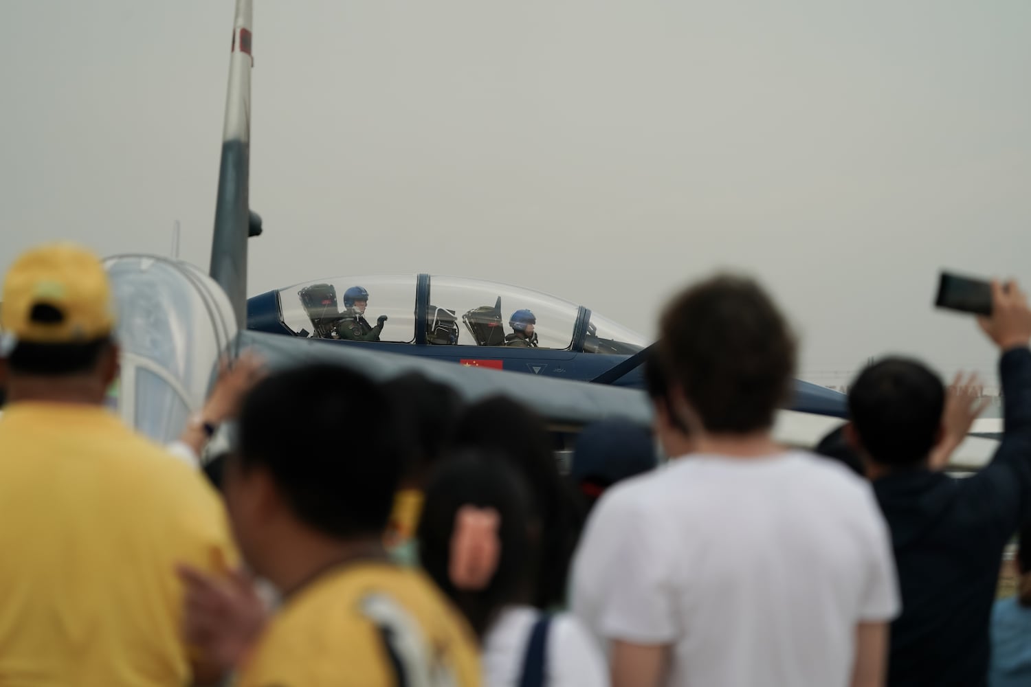 Chinese People’s Liberation Army Air Force pilots greet spectators as they taxi at Don Mueang air base in Bangkok, March 7, 2025.