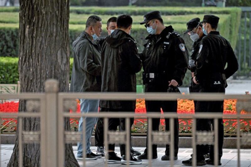 Police officers check the identification cards of people visiting Tiananmen Gate ahead of China's 20th Communist Party Congress in Beijing, Oct. 13, 2022. (Noel Celis/AFP)