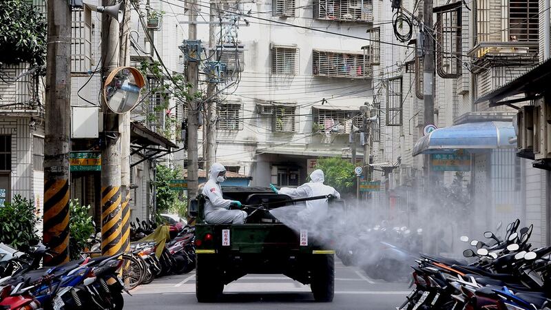 2021年5月27日，台湾新北市，身穿防护服的士兵在最近的冠状病毒病（COVID-19）感染激增之后，对街道的车辆进行消毒。（路透社）