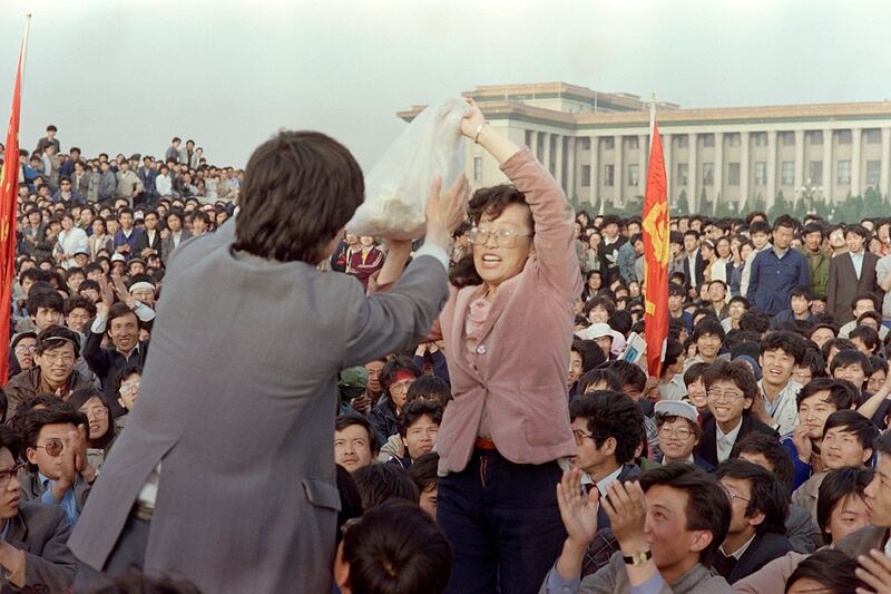 1989年5月15日，北京天安门广场，数万名学生和市民聚集，一名妇女（右）将一袋食物交给一名学生领袖。（法新社）