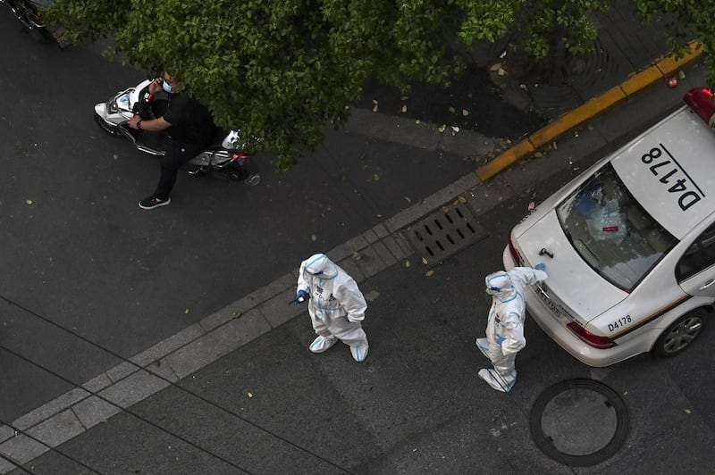 Policemen wearing personal protective equipment (PPE) stand on a street during a Covid-19 coronavirus lockdown in the Jing'an district in Shanghai, May 3, 2022. Credit: AFP