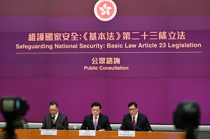 Hong Kong Chief Executive John Lee, center, Secretary for Justice Paul Lam, left, and Secretary for Security Chris Tang hold a press conference at government headquarters in Hong Kong on Jan. 30, 2024. (Peter Parks/AFP)