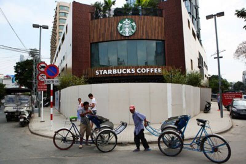 Xích lô chờ khách bên ngoài quán cà phê Starbucks đầu tiên tại thành phố Hồ Chí Minh hôm 31/1/2013. AFP photo