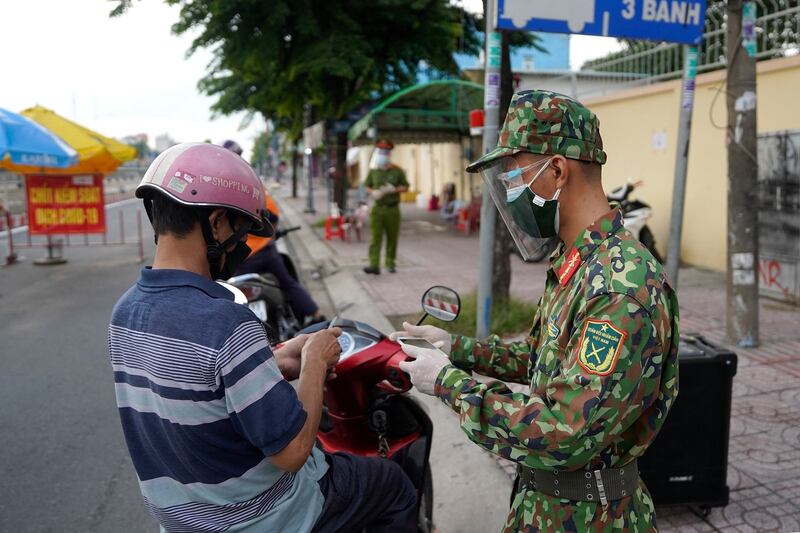 A Vietnamese military personnel (R) checks the travel documents of a motorist at a checkpoint in Ho Chi Minh City, Aug. 23, 2021, Credit: AFP