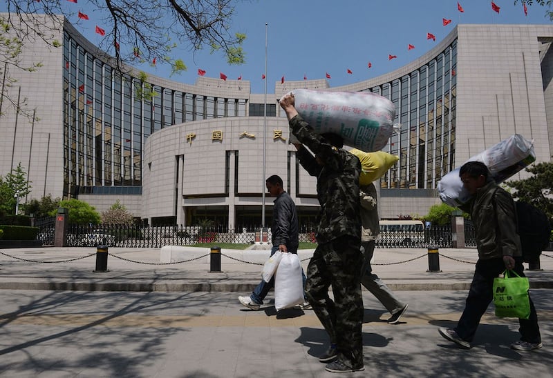 有学者表示，政府过紧日子，老百姓的日子将更加艰难。图为农民工经过中国人民银行。（法新社）