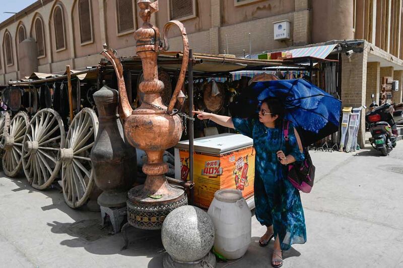 A woman stands next to a stall in Yarkant in northwestern China's Xinjiang region. Credit: Pedro PARDO / AFP