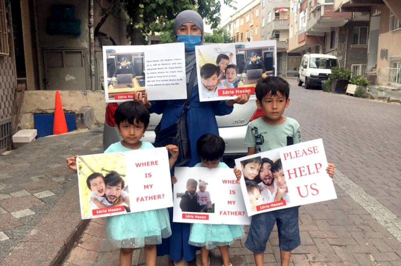 Buzeynur Obul, center, back, the wife of Idris Hasan, and their three children hold signs demanding Hasan's release, in front of the Moroccan consulate in Istanbul, Turkey, Dec. 16, 2021.