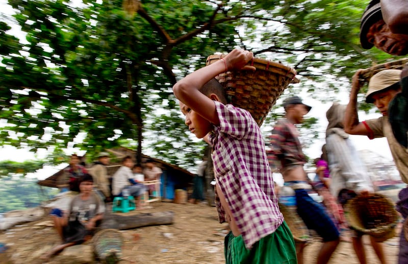 Eight-year-old Maung Kyaw, center, carries a basket of gravel, weighing about 19 kilograms (42 pounds) in Yangon, Myanmar, June 10, 2014. (Gemunu Amarasinghe/AP)