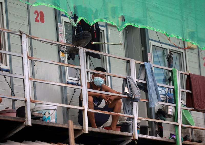 A Myanmar migrant worker passes the time on his balcony in a workers' dormitory in Bangkok, May 22, 2021.