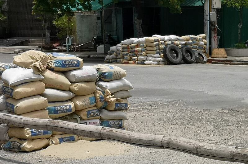 Sand bags stacked by the military and used as a checkpoint are seen along a road in Mandalay on June 23, 2021, following fighting in the streets of Myanmar's second-largest city. AFP