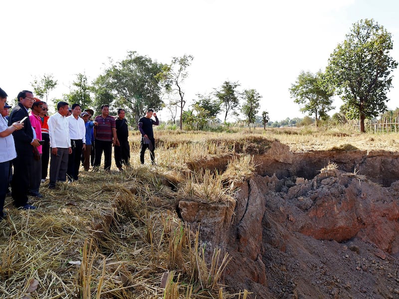 Khammouane Province Governor Vanxay Phongsavanh, left, and his delegation inspect a sinkhole in Pakpeng village, Laos, Dec. 4, 2024.