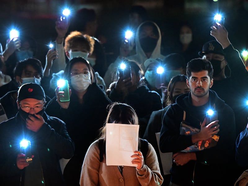 A woman holds a blank sheet of paper as demonstrators protest the deaths caused by an apartment complex fire in Urumqi, Xinjiang, China, at the Langson Library on the campus of the University of California, Irvine, in Irvine, California, on November 29, 2022.