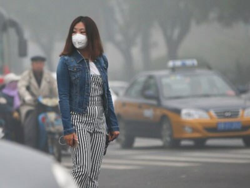 A Chinese pedestrian wearing a face mask walks on a road in heavy smog in Beijing, Oct. 14, 2016.