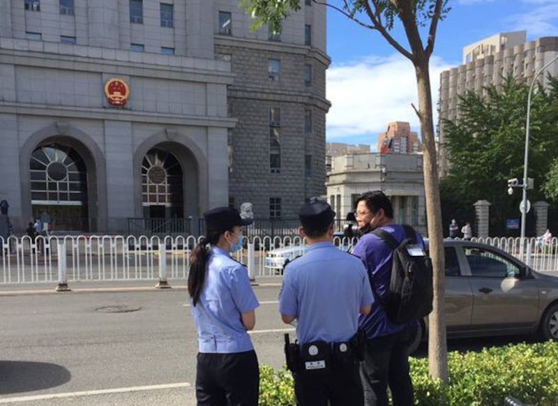 被拒采访的外媒记者在法院对开马路边拍摄，亦遭警察盘查。（小健拍摄/记者乔龙）