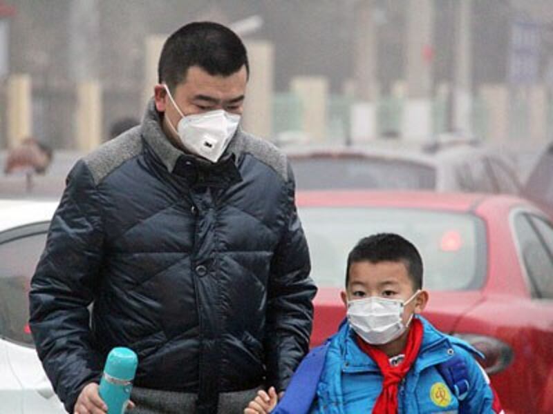 A Chinese father escorts his son, both wearing face masks to filter out air particles, to school in heavy smog in Qinhuangdao, northern China's Hebei province, Dec. 19, 2016.