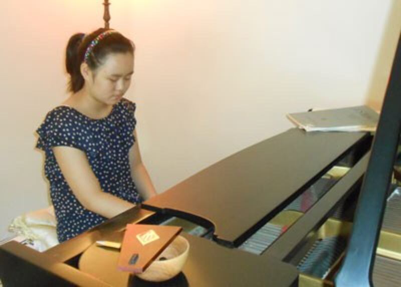 Zhang Anni plays the piano after arriving in the U.S., Sept. 7, 2013. Credit: Reggie Littlejohn