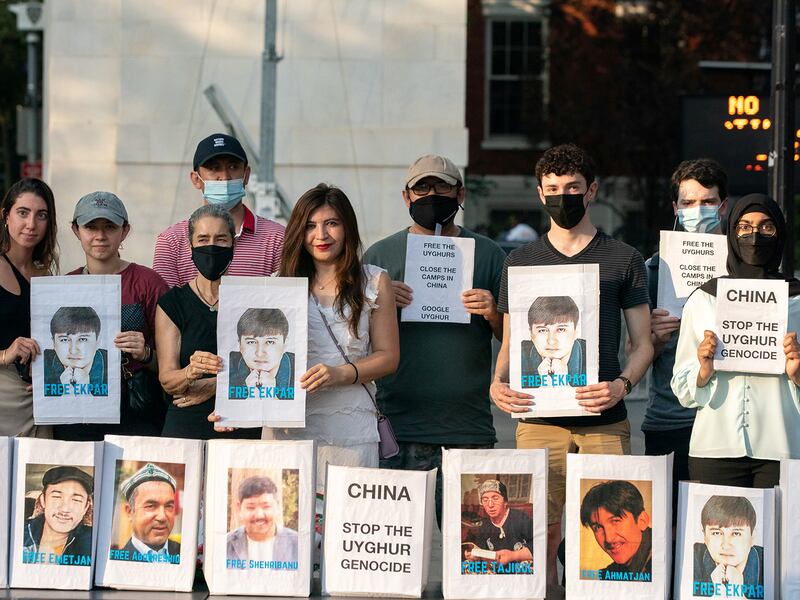 Protesters, and Asat's sister Rayhan Asat, center, hold photos of Ekpar Asat, during a rally in support of the Uyghurs, in New York City, August 12, 2021.