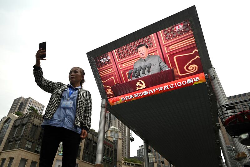 A woman takes a selfie as Chinese President Xi Jinping's speech is being broadcasted on a large screen in Beijing during celebrations of the 100th Anniversary of the founding of the Chinese Communist Party, July 1, 2021. Credit: AFP