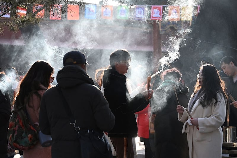 2024年2月10日，农历龙年大年初一，人们在北京雍和宫烧香祈福。（法新社）