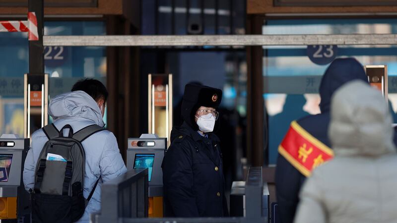 2021年1月28日，中国农历春节旅行季节开始前夕，一名铁路工作人员在冠状病毒病（COVID-19）爆发后戴着口罩和防护眼镜站在火车站的入口， 2021.路透社/卡洛斯·加西亚·罗林斯